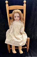 Full view of the doll seated on the chair