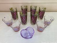 Front view close arrangement of the six grape motif highball glasses showing cluster details and leaves, highlighting the vibrant design.