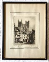 Photo of the full framed etching showing Lincoln Cathedral with Tudor-era houses and shops, framed in dark wood and gold.
