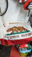 Photo showing California Republic banner with brown bear on grass and red text on white fabric.