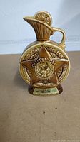 Front view of brown ceramic decanter shaped as a star with embossed inscriptions and design commemorating Knights of Pythias Centennial 1868-1968.