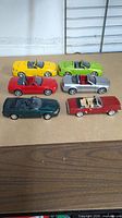 Six die cast Mustang convertible model cars in different colors arranged together on a table