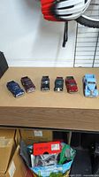 Photo showing all six diecast trucks lined up on a table with visible colors and styles