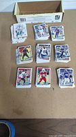 Multiple stacks of assorted football cards laid out on a surface with a box in the background.