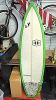 Front view of Hurricane surfboard with green rails, white deck, and logo.
