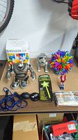 Photo showing all toys laid on table including robot toy, Q-Ba-Maze 2.0 box, silver metallic toy, colorful expandable ball, jump rope, glow stick package, toy car and mini cardboard set