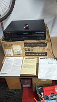 Marantz 5 disc CD changer resting on original box with RCA cables on top, accompanied by manuals.