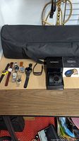 Full lot of men's watches displayed on table with a black carrying case and Movado Connect 2.0 box