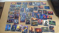 Overview photo showing a spread of 48 non-sports gaming trading cards with colorful fantasy and sci-fi themes on a tabletop.