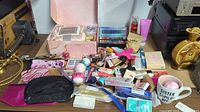 Full overview of lot contents showing bath bombs, false eyelashes, lipsticks, gloves, skincare tubes, eyeshadow palette, pillowcase box, and coffee mug