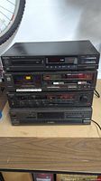Stacked Technics stereo components showing front panels of amplifier, cassette deck, CD player, and CD changer