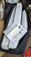 The carry bag containing white boxes presumed to hold umbrella light components and a quick reference guide placed inside the bag.