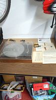 Turntable with dust cover on tabletop next to original paperwork and accessories.