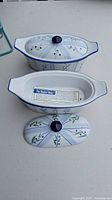 Two ceramic butter boats with matching lids, white with blue trim and floral pattern.
