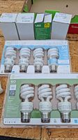Lot showing eight light bulbs: two boxes of 4-pack CFL bulbs, one box of 3-pack CFL bulbs, and three sealed boxed LED bulbs.
