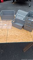 Set of eight gray plastic organizers and baskets of various sizes displayed on wooden surface
