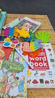 Lot of colorful pop-it toys, children's books, and educational materials on a wooden table.