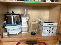 Crockpot slow cooker SCR300-S-BR, Rival ice crusher, Cuisinart blender box and blender jar inside wooden cabinet