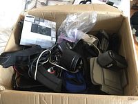 Box filled with cameras, lenses, straps, pouches and cables
