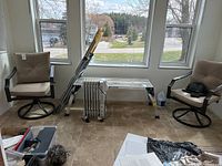 Two swivel chairs with light brown cushions by a large window, showing the overall pair for sale.