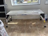 Photo of aluminum Werner platform ladder from front showing overall structure and Werner brand label.