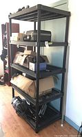 Full view of the black resin five-tier shelving with various items on shelves.