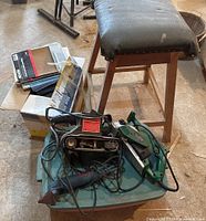 Lot showing a wood stool with padded black cover, box containing sandpaper sheets, and three sanders (two Craftsman corded sanders and one Ryobi detail sander) atop a green plastic container.