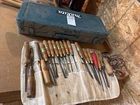 Canvas roll of 17 chisels laid out in front of a teal Makita tool case