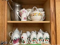Front view of wooden shelf containing assorted tea and coffee ware