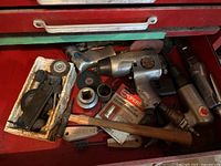 Photo showing pneumatic tools and small hand tools including wire brushes, hammer, and a packaged hydraulic coupler in a red drawer.