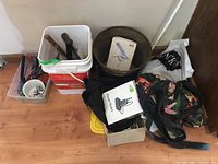 Plastic bins and bags on floor containing varied tools, electrical items, and accessories