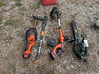 Yardworks blower and two trimmers (Fiskars and Black & Decker) laid out on grass.