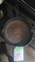 Top view of the round cast iron skillet pan on a stove, showing surface discoloration and wear.