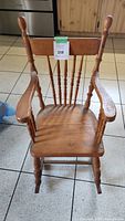 Front view of the child's wooden rocking chair showing turned spindle back, armrests, and the overall condition.
