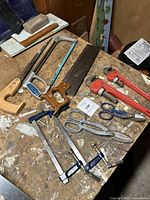 Overview of all tools arranged on workbench to show included items: saws, wrenches, clamps, snips.