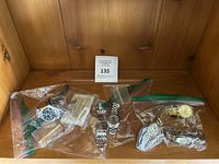 Four wristwatches in plastic bags arranged on wooden surface.