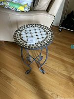 Full view of the outdoor table next to a sofa showing entire piece and mosaic top.