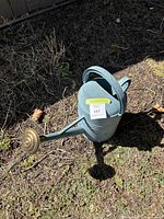 Light green plastic watering can made to look like metal, visible from above showing the top and handle