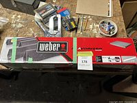 Box of Weber flavorizer bars on a workbench, other tools and parts visible in background.