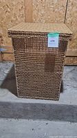 Front view of rectangular woven wicker basket with lid in natural brown color.