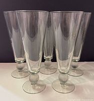 Group of four clear vintage pilsner beer glasses showing the golf ball detail on the stems.