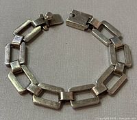 Top view of sterling silver rectangular linked bracelet with box clasp laid flat showing length and design.