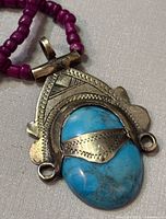 Close-up of the silver pendant with the blue turquoise stone showcasing engravings and design details.