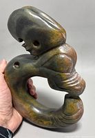 Side view showing dragon head details and curved hook body with multicolor jade tones.