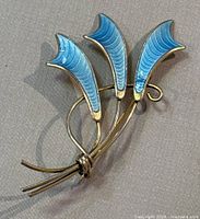 Front angle of silver brooch with blue enamel floral petals showing design and condition