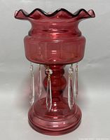 Side view of the ruby red glass mantle luster showing the ruffled top and hanging clear crystal prisms
