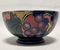Side view of vintage Royal Stanley Ware bowl showing hand-painted fruit and leaf design on dark blue background.