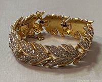Photo showing folded view of TRIFARI bracelet highlighting the rhinestone encrusted leaf design and the gold-tone metal backing with clasp.
