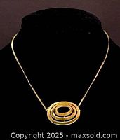 Front view of the necklace on a black display stand showing the oval concentric rings pendant and chain.