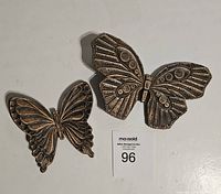 Two dark copper finish metal butterfly wall decorations with embossed designs, shown from front.